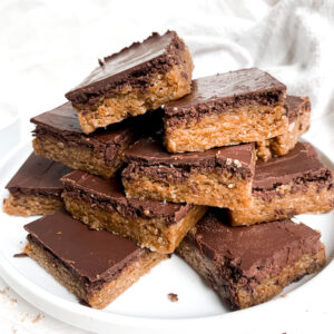 the batch of cookie bars on a white plate stacked up