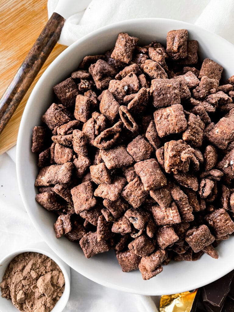 protein puppy chow in a white bowl next to chocolate protein powder