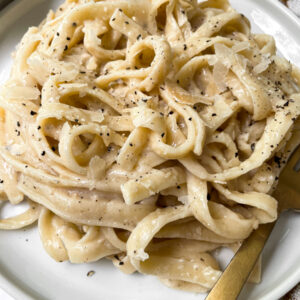 alfredo on a white plate with gold fork