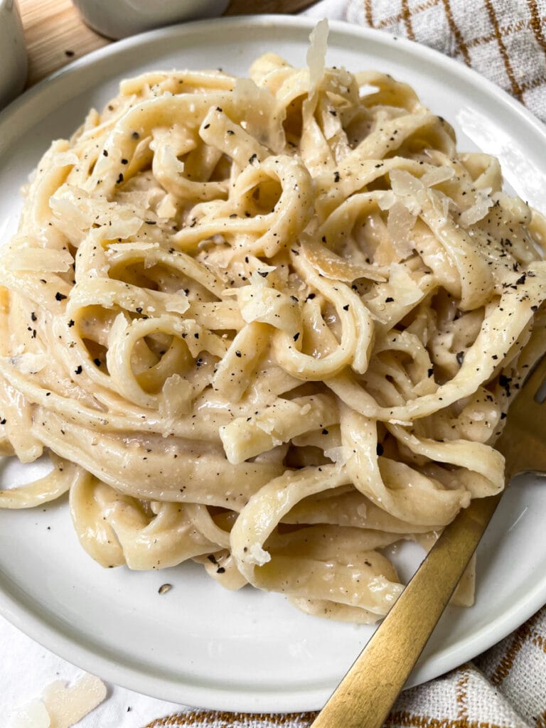 alfredo on a white plate with gold fork