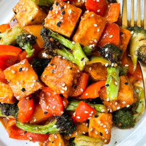 close up of orange tofu with veggies and sesame seeds