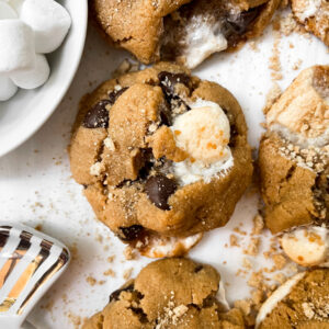 close up of smores cookies next to marshmallows in a white bowl