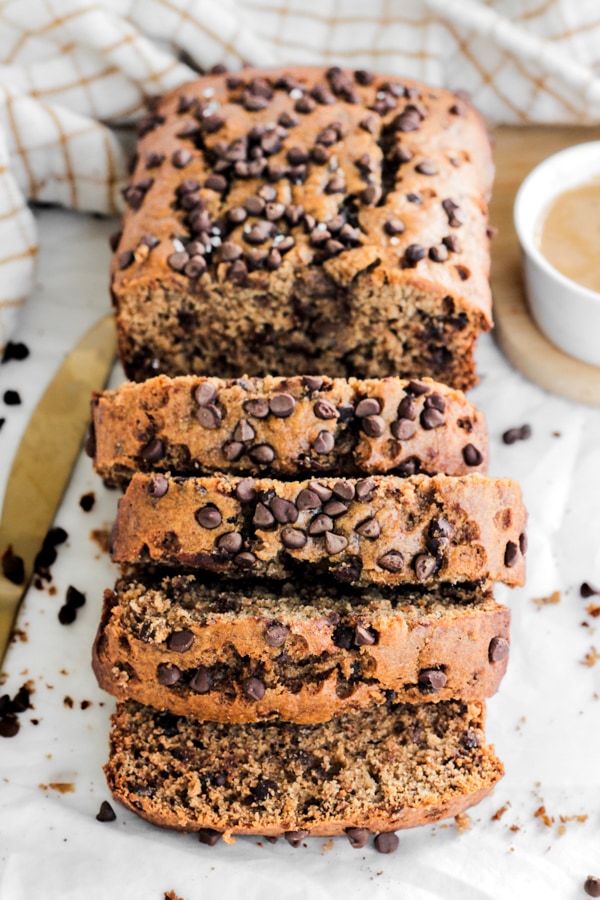 a loaf of almond butter banana bread, sliced topped with extra chocolate chips