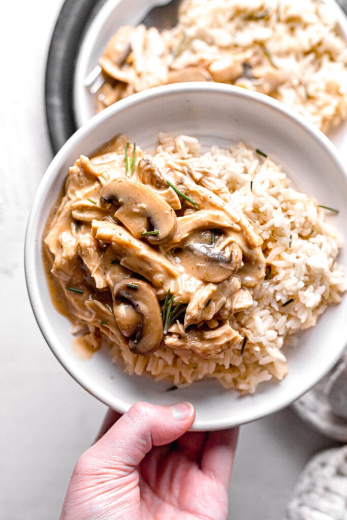 holding a plate of slow cooker cream of mushroom chicken and rice