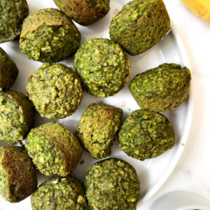 top view of the mini banana spinach muffins on a white plate next to a ramekin of oats