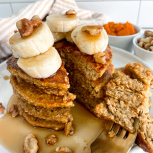 protein pumpkin pancakes stacked on each other with sliced bananas