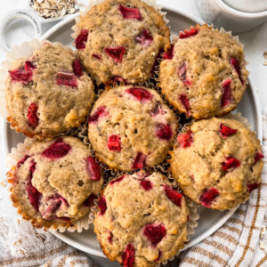strawberry banana muffins after baking on a white plate next to oats