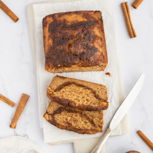 sliced cinnamon banana bread on a cutting board with a butter knife.