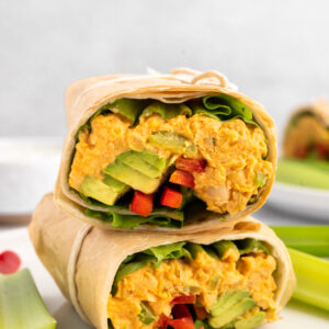 Buffalo Chickpea Wrap cut in half stacked on top of each other on a plate.