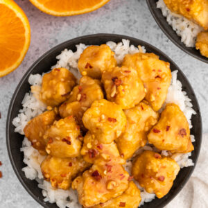 air fryer orange chicken in a black bowl with rice next to an orange