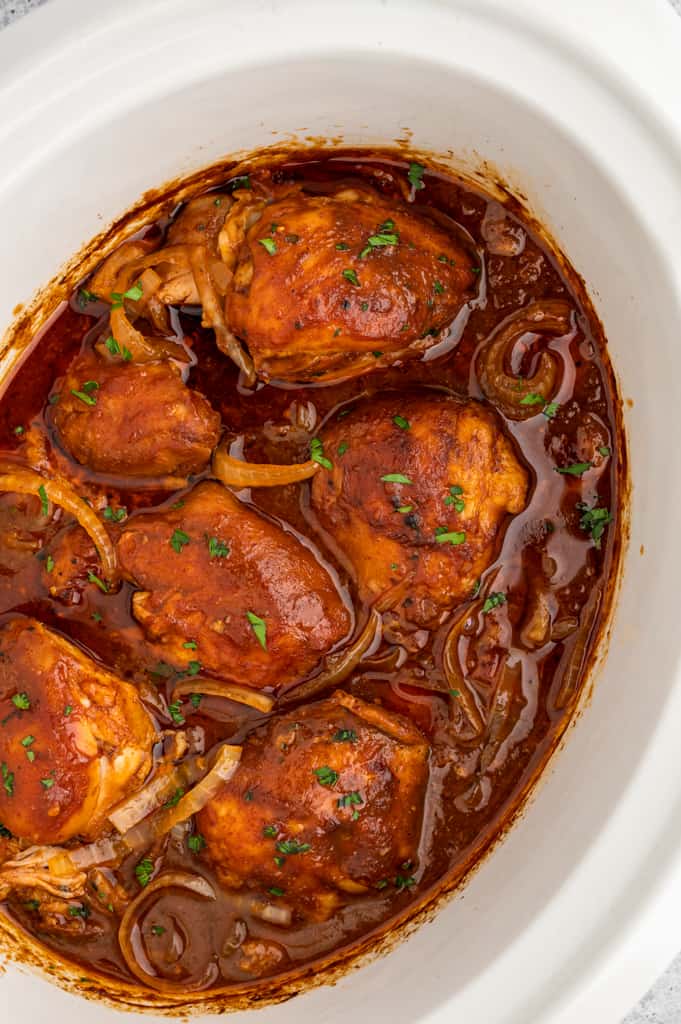 top view of barbecue chicken thighs in a white crockpot.