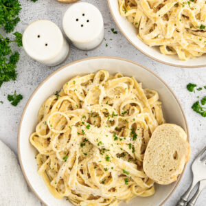 Two bowls of cottage cheese alfredo with bread.