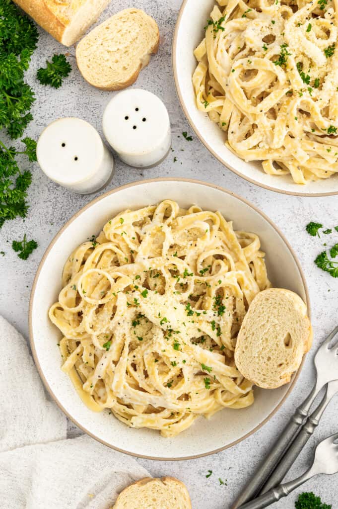 Two bowls of cottage cheese alfredo with bread.