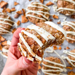 Holding a no bake apple cinnamon oatmeal cookie with a bite taken out.